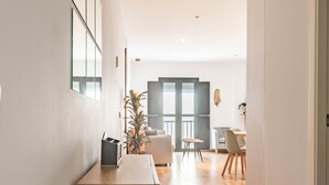 Et moderne interiør med et træskrivebord, en potteplante og et spiseområde med stole og bord.