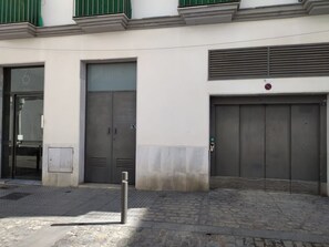 Ein Gebäude mit zwei großen grauen Türen, einem kleinen Fenster und einem grünen Vordach.