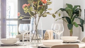 Et spisebord med hvide tallerkener, vinglas og en vase med blomster.