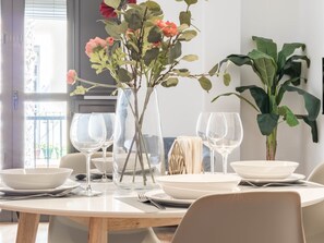 Ein Esstisch mit weißen Tellern, Weingläsern und einer Blumenvase.