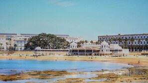 Ein Küstenhotel mit Blick auf den Strand, einem großen Baum und mehreren Gebäuden.