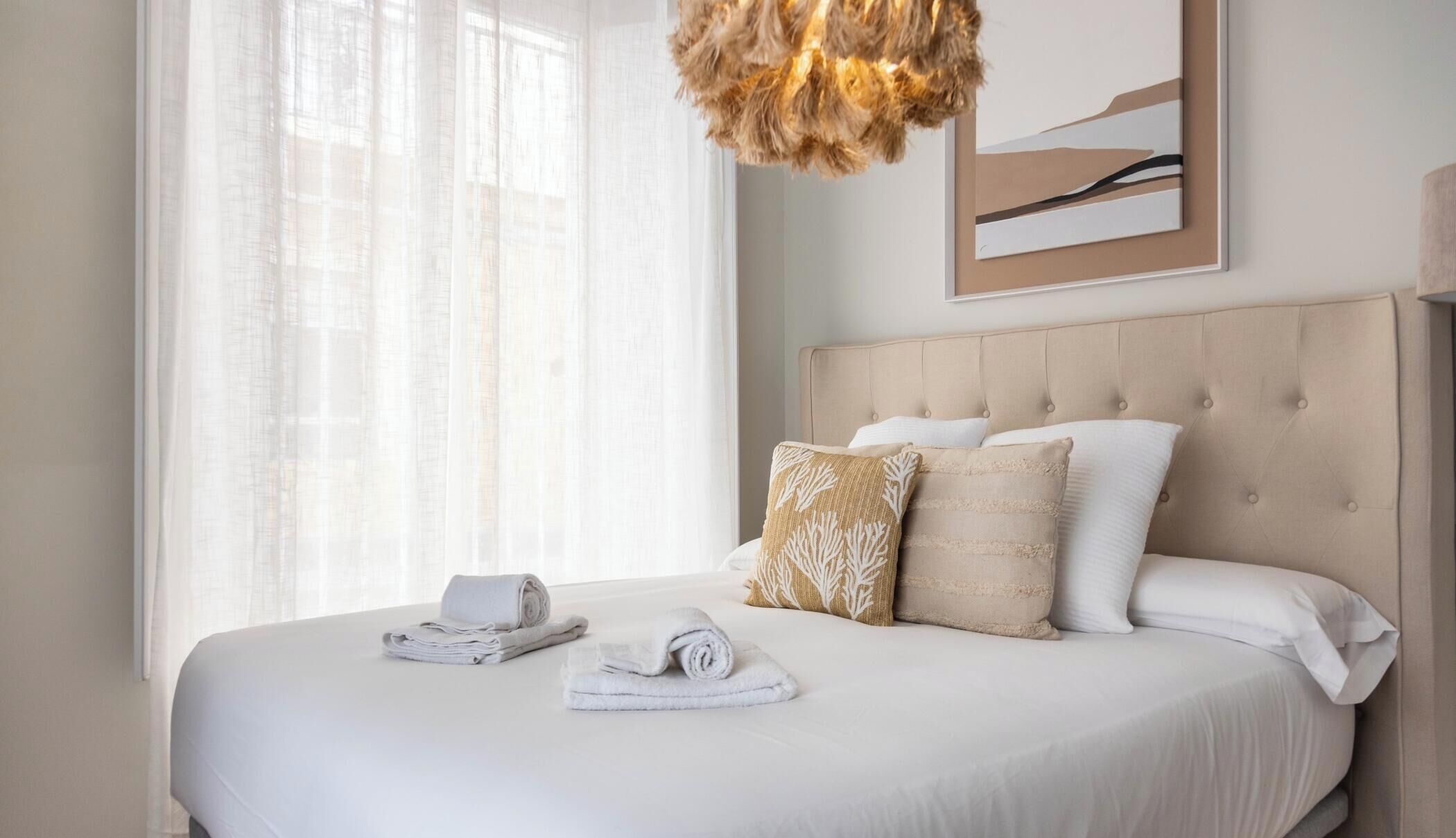 A neatly made bed with white linens, a headboard, and decorative pillows.
