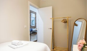 A bedroom with a bed, a wooden drying rack, a mirror, and a bathroom visible through an open door. - Tailor's Home by Cadiz Time (Ciudad de Cádiz)