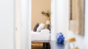 A hotel room with a bed, bedside table, lamp, and a plant. - Tailor's Home by Cadiz Time (Ciudad de Cádiz)