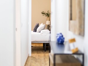 A hotel room with a bed, bedside table, lamp, and a plant. - Tailor's Home by Cadiz Time (Ciudad de Cádiz)