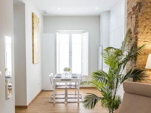 A modern dining area with a white table and chairs, a large window, and a plant. - Nature Home by Cadiz Time (Cádiz)