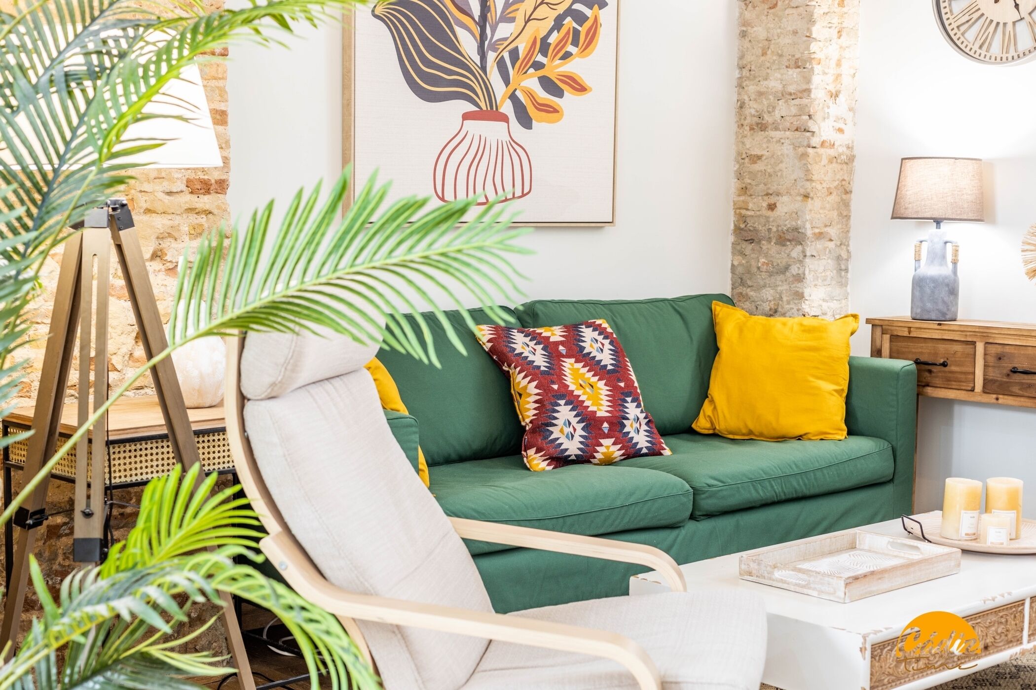 A green sofa with patterned cushions, a tripod stand, and a table with candles.