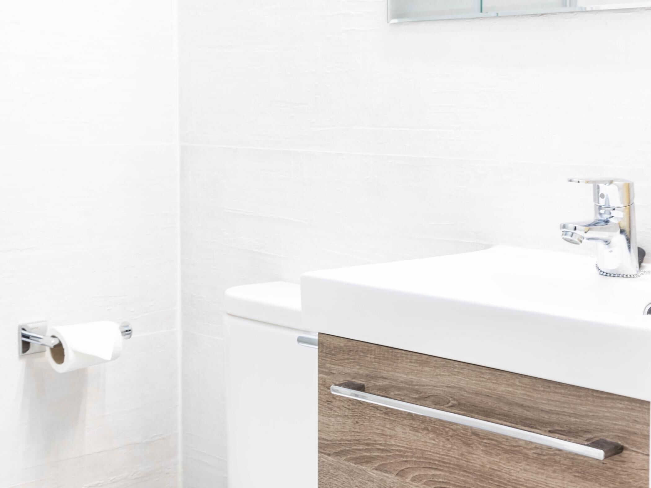 Ein Badezimmer mit einem weißen Waschbecken, einer Toilette und einem Handtuchhalter.