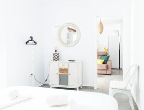 A modern, minimalist bedroom with a bed, a white dresser, a hanging light, and a mirror. - Casa Rehala PAYA by Cadiz Time (Ciudad de Cádiz)