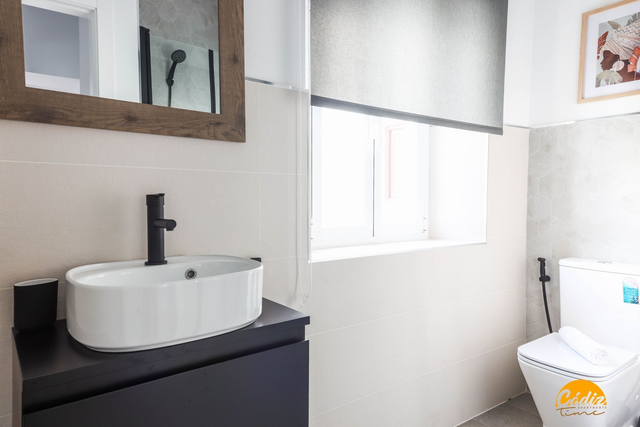 Une salle de bain avec un lavabo blanc, un robinet noir et des toilettes blanches.