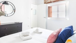 Una camera da letto moderna con un letto, una cassettiera, uno specchio e una finestra.