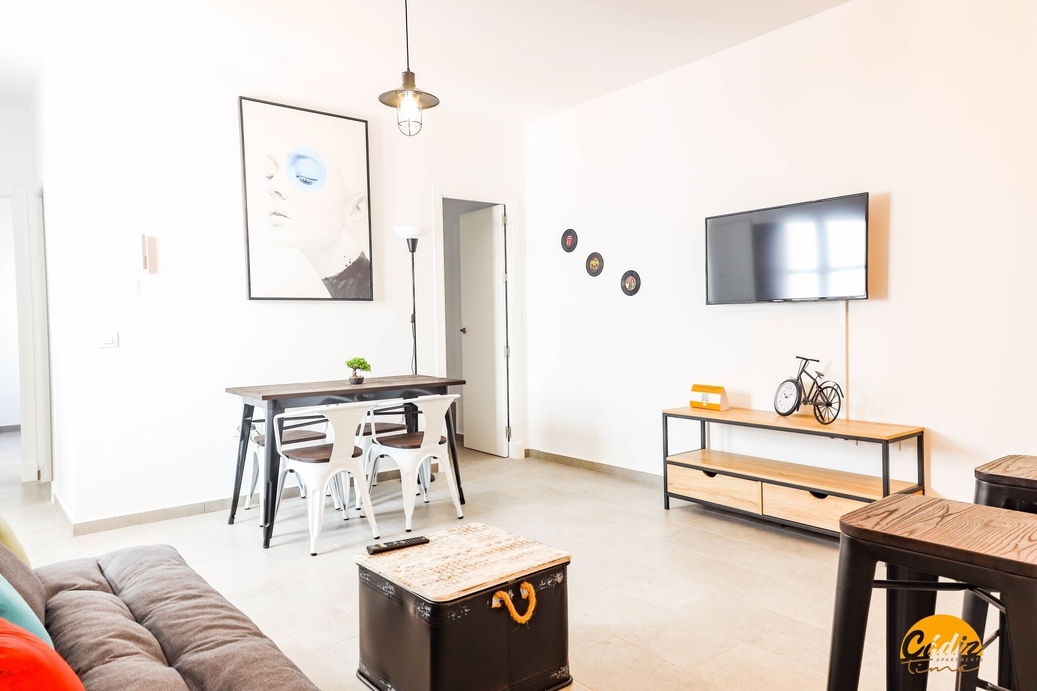 Een woonkamer met een bank, een salontafel, een televisie, een eettafel met stoelen en een bankje.