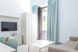 A modern living room with a flat-screen TV, a white cabinet, a sofa, a table, and a window with curtains. - The Yellow House by Cadiz Time (Ciudad de Cádiz)