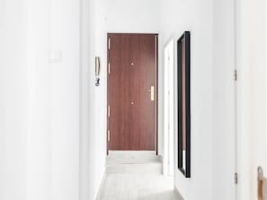 A hallway with a wooden door, a white wall, and a framed picture. - The Yellow House by Cadiz Time (Ciudad de Cádiz)