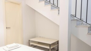 A room with a white door, a small table with a metal frame, and a staircase with a black railing. - Loft Santa Maria by Cadiz Time (Ciudad de Cádiz)