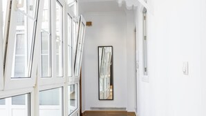 A hallway with white walls, a wooden floor, and a large mirror on the wall. - La Luz de La Viña -by Cadiz Time (Ciudad de Cádiz)