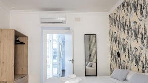 A bedroom with a bed, a wooden wardrobe, a mirror, and a wall with a leaf pattern. - La Luz de La Viña -by Cadiz Time (Ciudad de Cádiz)