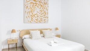 A bedroom with a large bed, two bedside tables, a wall-mounted artwork, and a neatly made bed. - Apartamento Bike by LiveWork (Ciudad de Cádiz)