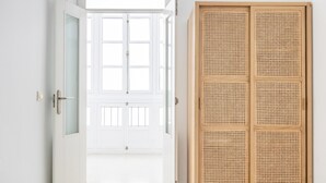 An open door leading to a room with a large window, a wooden wardrobe, and a white wall. - Apartamento Bike by LiveWork (Ciudad de Cádiz)