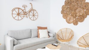A modern living room with a grey sofa, a wall-mounted bicycle decoration, and a cluster of circular wall art. - Apartamento Bike by LiveWork (Ciudad de Cádiz)