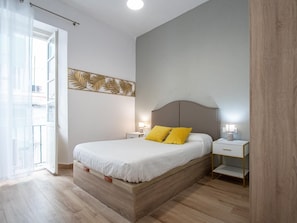 Ein Schlafzimmer mit Bett, Nachttischen, einer Wandleuchte und einem Fenster mit Blick.
