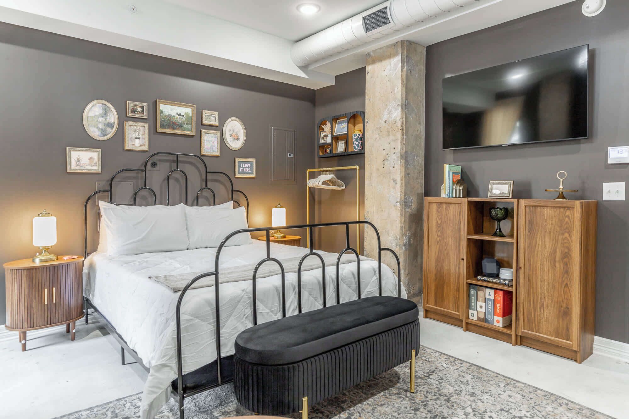 A bedroom with a bed, bedside tables, a bench, a wardrobe, and a TV.