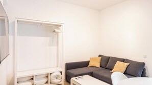 A modern living room with a grey sofa, two cushions, a white coffee table, and a white wardrobe with a mirror. - Bajo Teatro Falla by Cadiz Time (Ciudad de Cádiz)