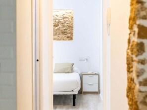 A bedroom with a bed, a nightstand, a lamp, and a textured wall art piece. - Bajo Teatro Falla by Cadiz Time (Ciudad de Cádiz)