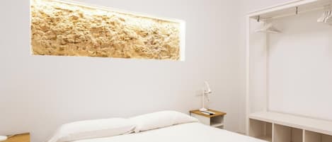 Une chambre d’hôtel moderne équipée d’un lit, d’une table de chevet, d’un climatiseur fixé au mur et d’une grande fenêtre offrant une vue intéressante.