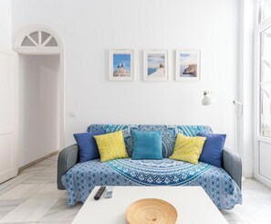 Ein Wohnzimmer mit einem gemusterten Sofa, einem Couchtisch und gerahmten Bildern an der Wand.