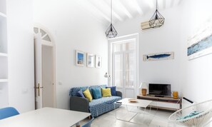 Ein modernes Wohnzimmer mit einer Couch, einem Fernseher, einem Esstisch und einem Sessel.