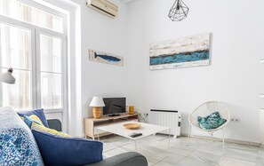 Ein modernes Wohnzimmer mit Sofa, Couchtisch, Fernseher und Bildern an den Wänden.