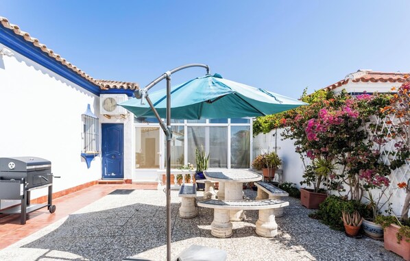 Eine Terrasse mit Grill, Sitzgelegenheit im Freien und Kübelpflanzen.