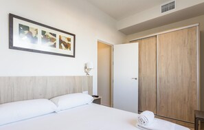 Ein Hotelzimmer mit einem Bett, einem Holzschrank, einem gerahmten Bild an der Wand und einer Nachttischlampe.