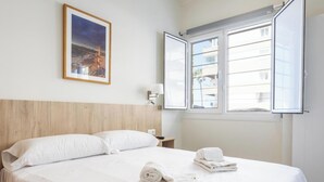 A hotel room with a bed, a nightstand, a window, and a framed picture on the wall. - Delfin Azul 3 by Cadiz Time (Cádiz)