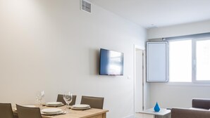 A modern living room with a dining area, a flat-screen TV, a sofa, and a window. - Delfin Azul 3 by Cadiz Time (Cádiz)
