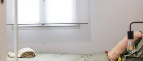 Et værelse med en seng, et vindue og en lampe.