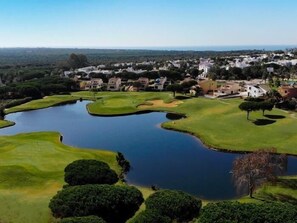 A golf course with water hazards and a residential area in the background. - Retama Golf by Cádiz Time (Chiclana de la Frontera)