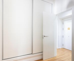 Ein Zimmer mit Schiebetür, Holzboden und weißer Wand.
