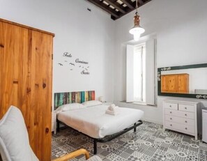 Ein Schlafzimmer mit einem Bett, einem Holzschrank, einer Kommode, einem Fenster und einer Wand mit Vogelmotiv.