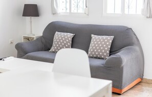 Ein graues Sofa mit Kissen mit Sternenmuster, ein weißer Tisch und eine Lampe auf einem Nachttisch.