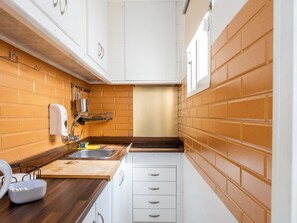Eine Küche mit Holztischplatte, weißen Schränken und orangefarbenen Backsteinwänden.