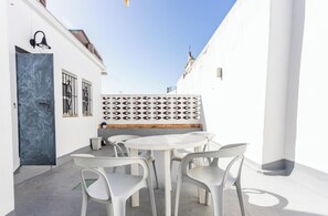 Un bâtiment blanc avec une porte bleue, un mur orné de motifs et un espace détente comprenant une table et des chaises.