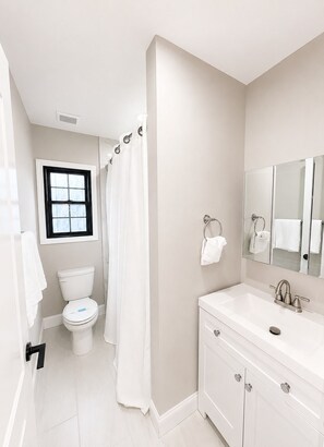 A bathroom with a toilet, a shower curtain, a sink with a mirror, and a window. - 2 Apts, 2bd 2ba, Sleeps 10, Clean & Reliable, Near NYC (Scotch Plains)