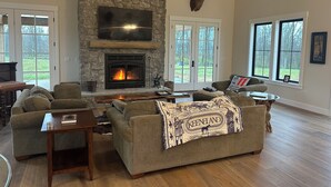 Un salón amplio con chimenea de piedra, asientos cómodos y ventanas grandes.