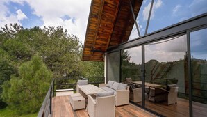 A modern outdoor deck with wicker furniture and a glass enclosure. - Paseo del Llano Cabañas & Suites (Mazamitla)