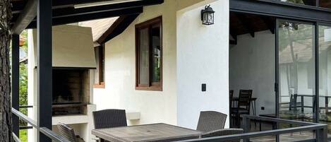 An outdoor patio with a table and chairs, a grill, and a stone wall.