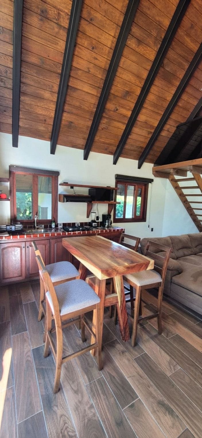 A kitchen with a wooden table and chairs, a built-in oven, and a staircase leading to an upper level.