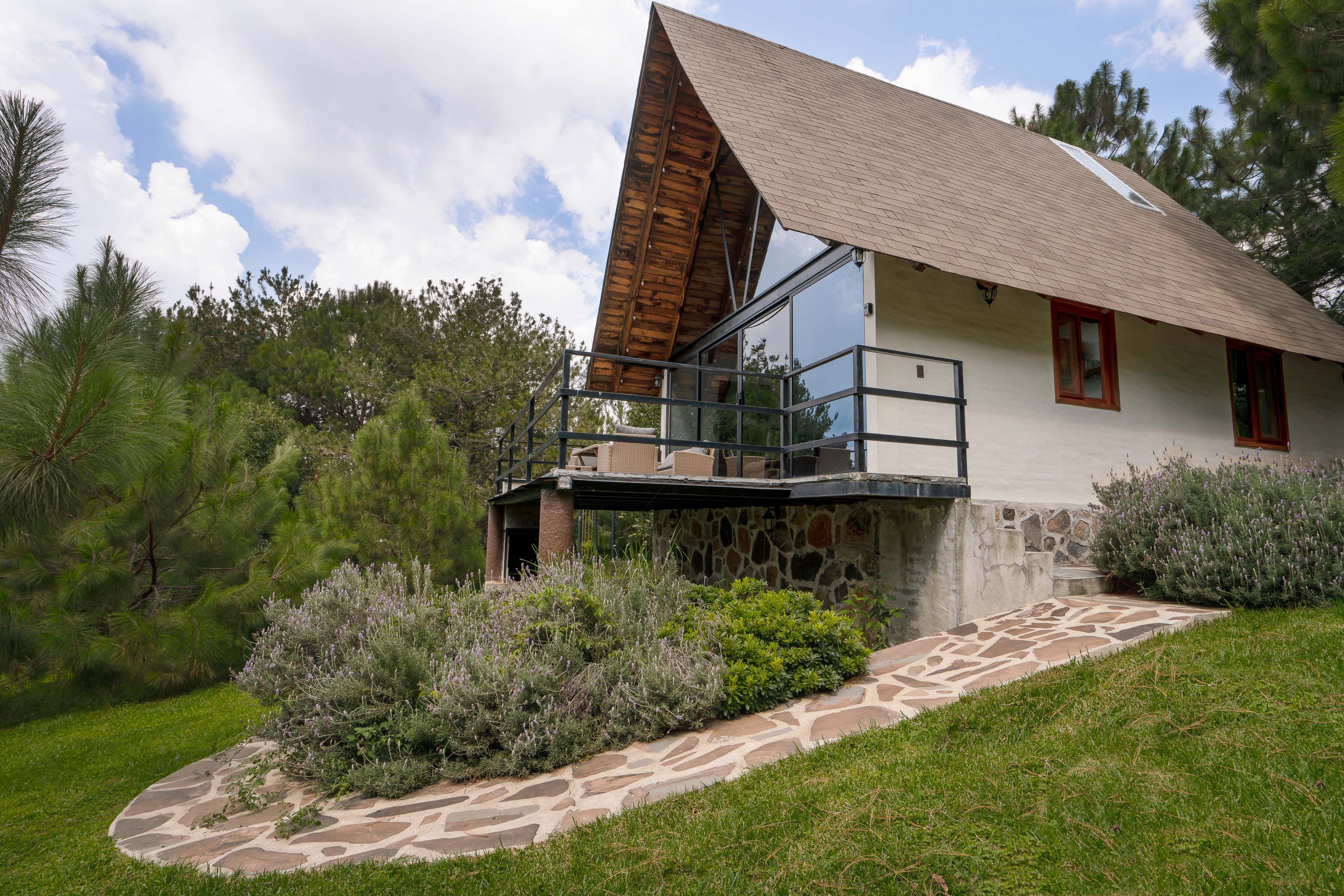 Una casa con base de piedra, una terraza de madera y un amplio ventanal de vidrio.