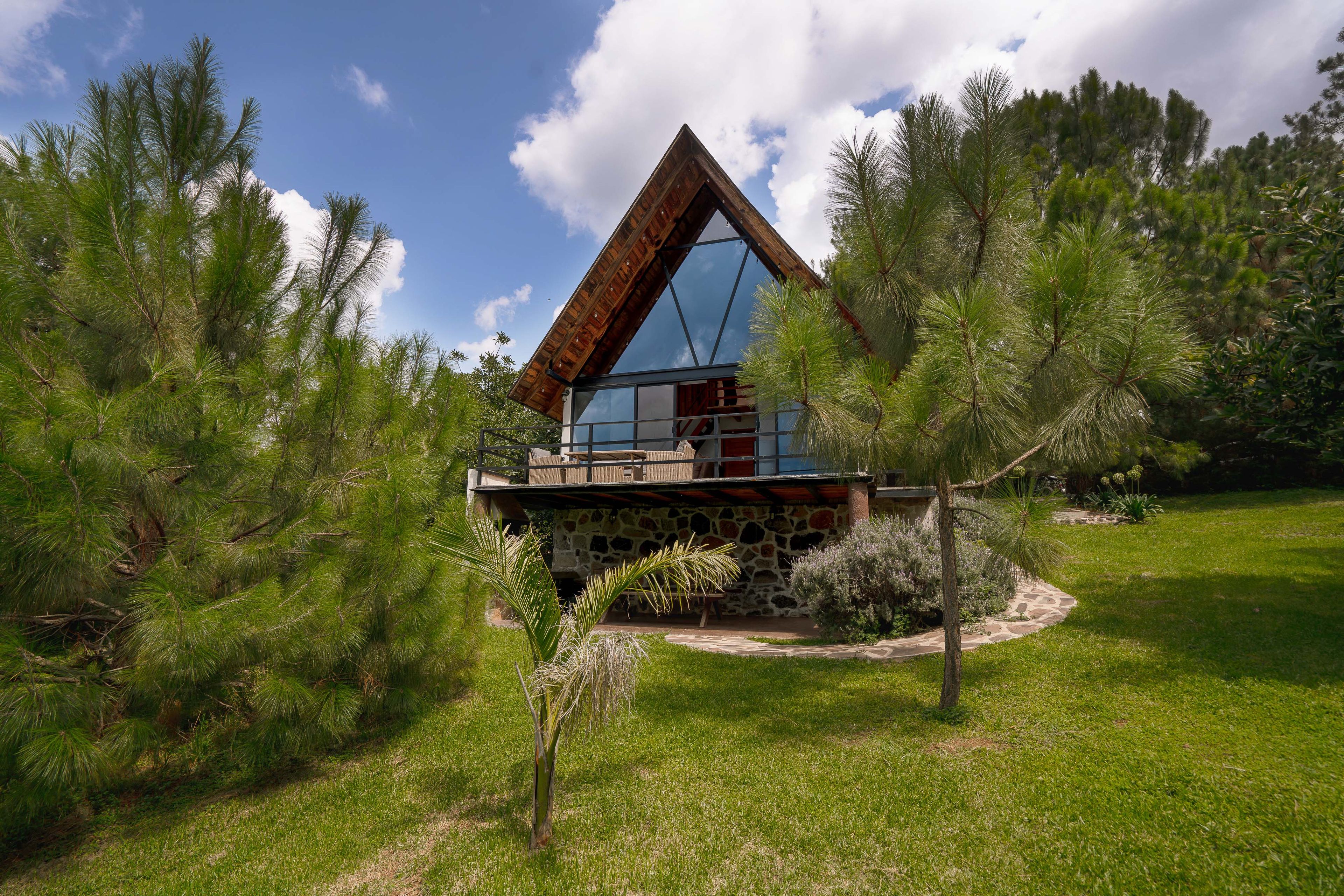 A modern house with a stone foundation, a wooden deck, and a glass conservatory.